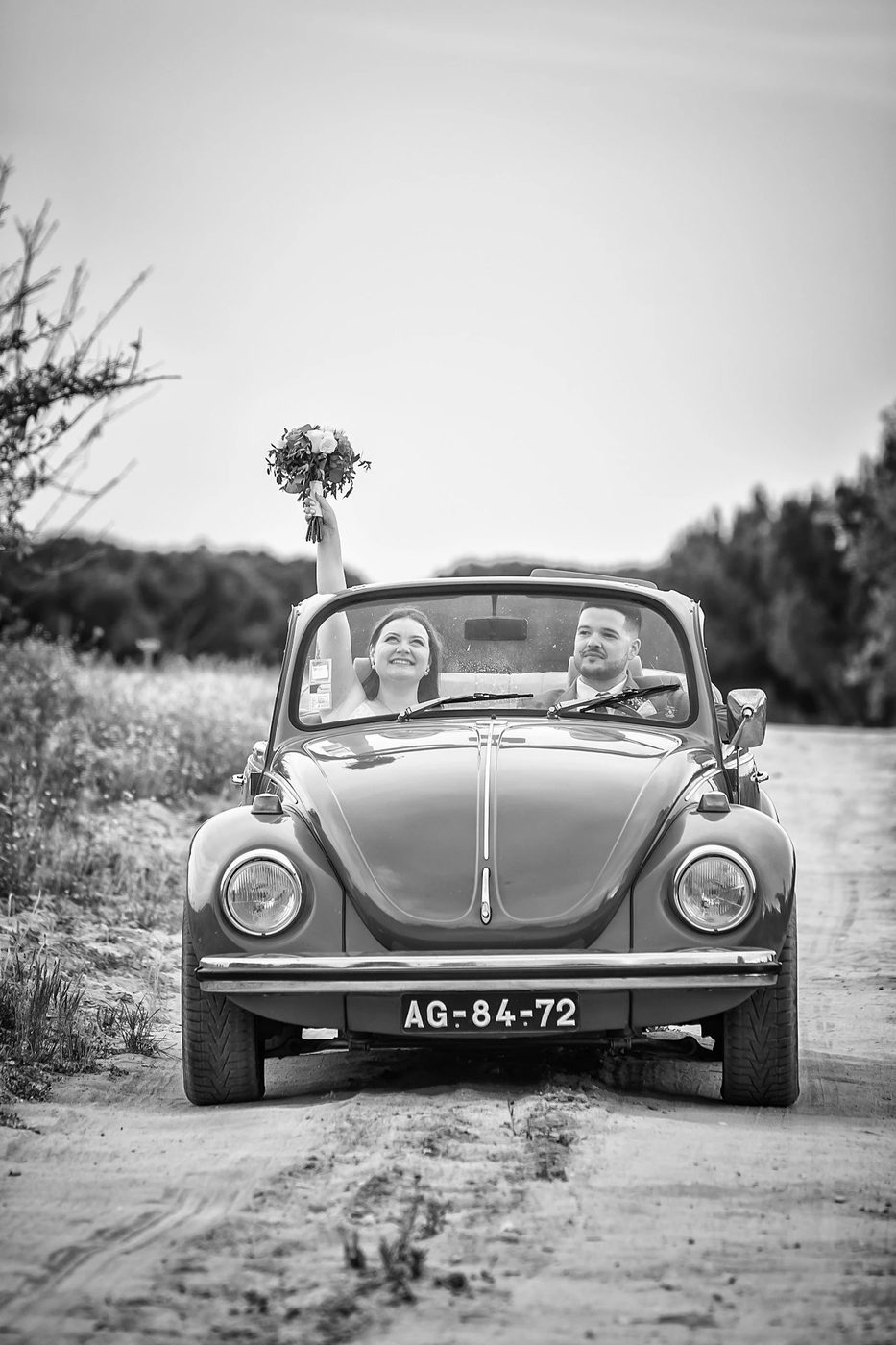 Noivos num Volkswagen Carocha vintage, fotografia a preto e branco