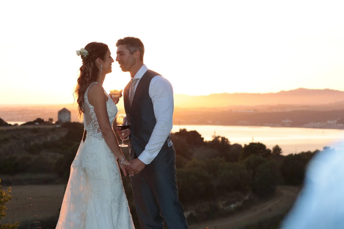 Noivos em silhueta ao pôr-do-sol, brinde de casamento em Portugal